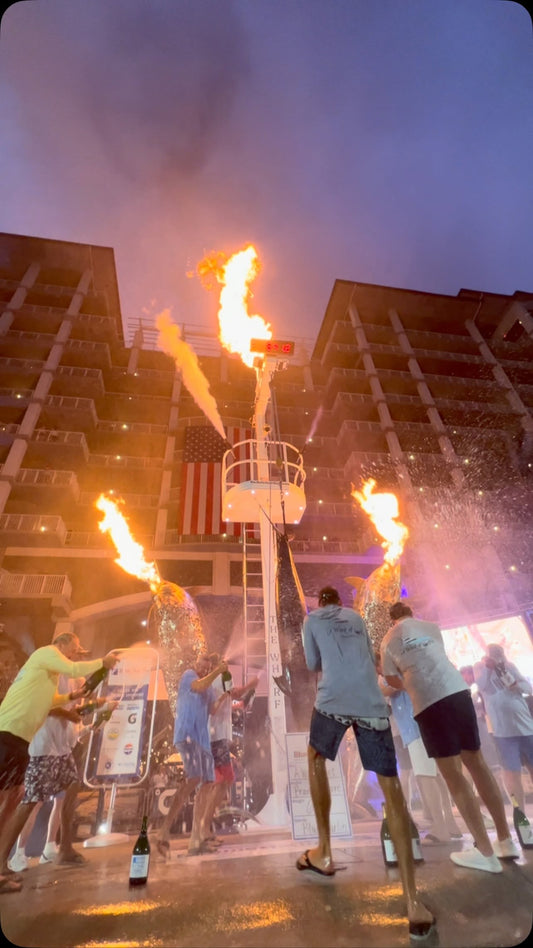 A Work of Art crew sprays champagne under the fire cannons at The Wharf Marina after winning the 2026 Blue Marlin Grand Championship in Orange Beach, Alabama