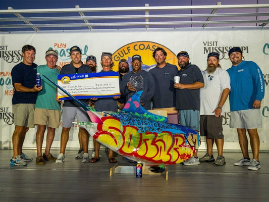Team Fleur de Lis hoists a giant grand champion check beside their spray-painted blue marlin trophy at the 2026 Mississippi Gulf Coast Billfish Classic in Biloxi.
