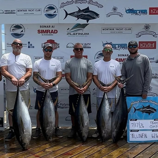 Team O.H.M. anglers hold yellowfin tuna on the Montauk Canyon Challenge weigh stage, whiteboard dated 7/17/26